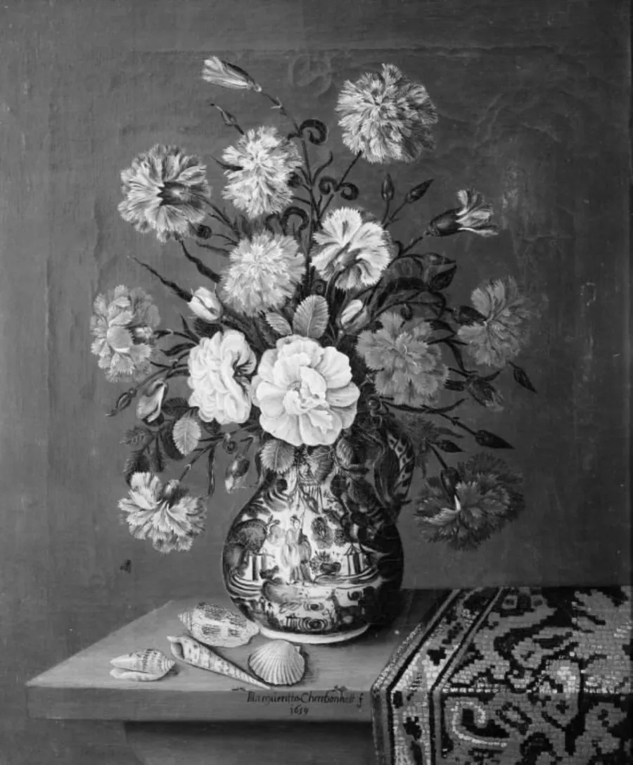 På et træbord, hvorpå der ligger et tyrkisk tæppe samt nogle konkylier står en blå porcelænskrukke med blomster by Margueritta Charbonnet
