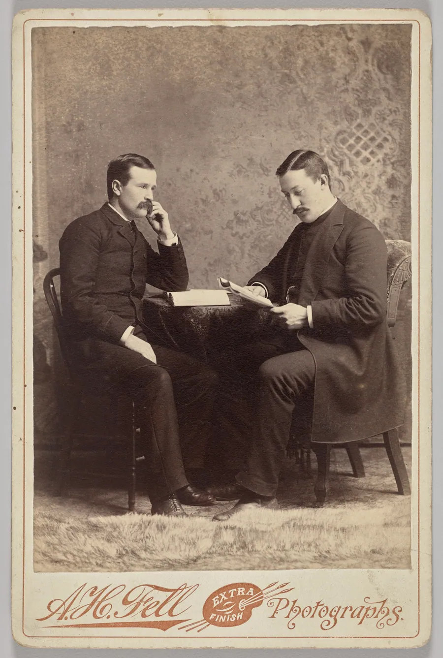 Untitled (seated portrait of two men, one with a book, the other reading a magazine) by A.H. Fell