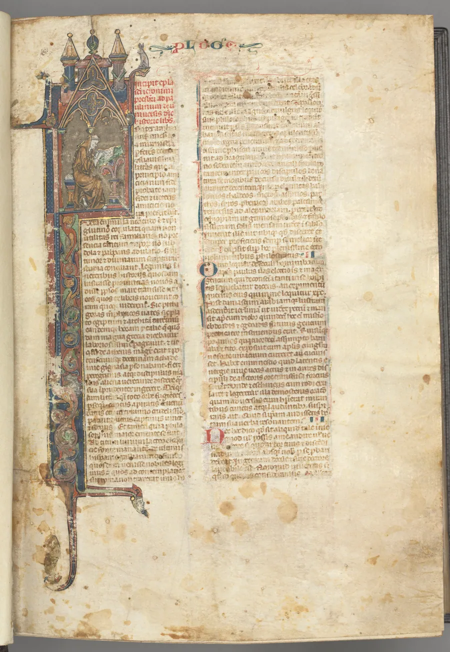 Fol. ir: Prologue, St. Jerome, large historiated initial I, the saint in a brown habit writing at a desk in a gothic architectural frame, with full-length border of foliage and small hybrids, a hare, a dog and a grotesque perched on the foliage extensions