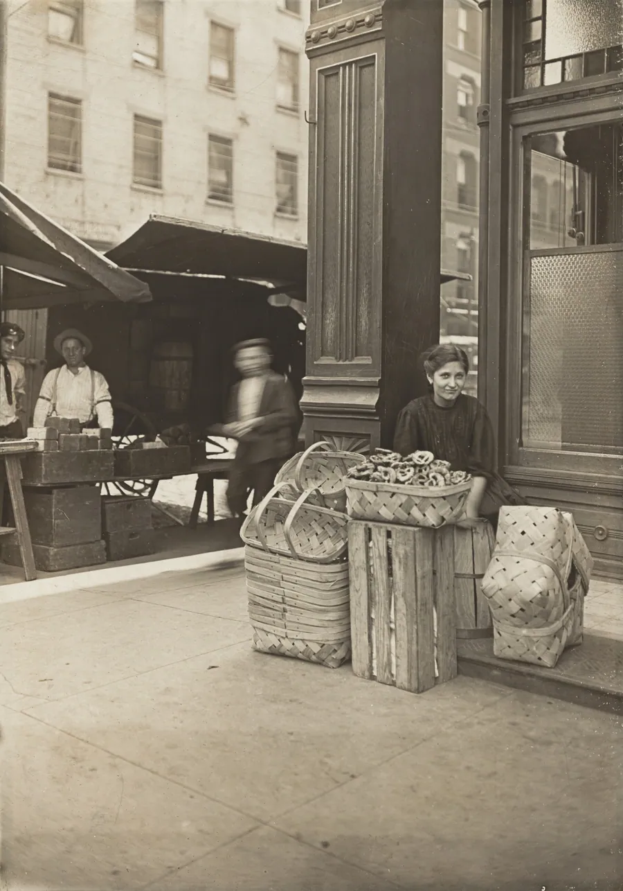 Lena Lochiavo - 11 years old, basket (and pretzel) seller, at Sixth Street Market in front of saloon entrance, Cincinnati, Ohio by Lewis Wickes Hine