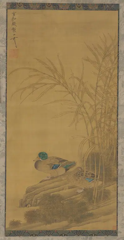 Two ducks among reeds at the water's edge