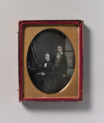 [Two Young Men in Bow Ties, One Seated Holding a Book, One Standing]